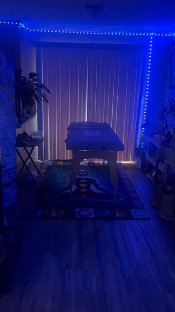 Her treatment room: massage table set over a chakra mat, lit in blue